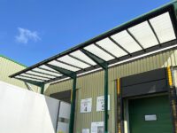 A green loading bay canopy covering two loading bays