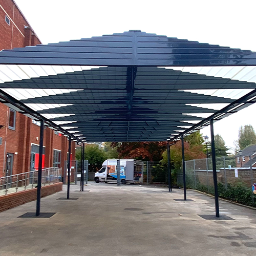 A large blue playground canopy covering a concrete playground