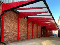 A red loading bay canopy attached to a brick building