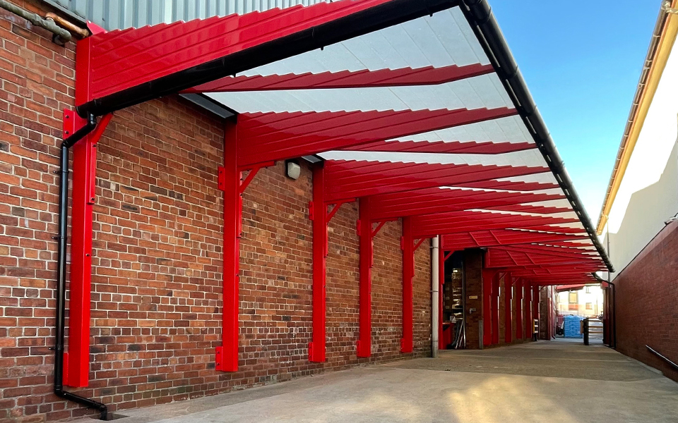 A red loading bay canopy attached to a brick building